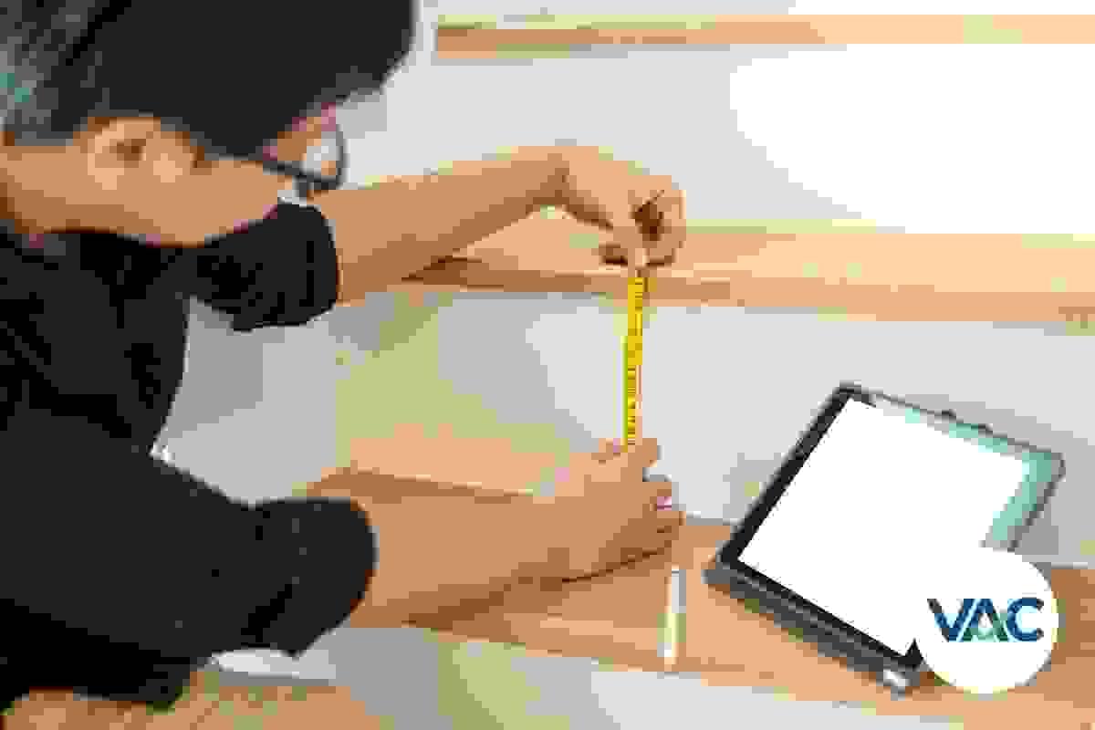 A male access consultant is measuring the height, or riser, or a stairway and is using a tape measure, while looking at a tablet PC screen (2) A male access consultant is measuring the height, or riser, or a stairway and is using a tape measure, while looking at a tablet PC screen (2)