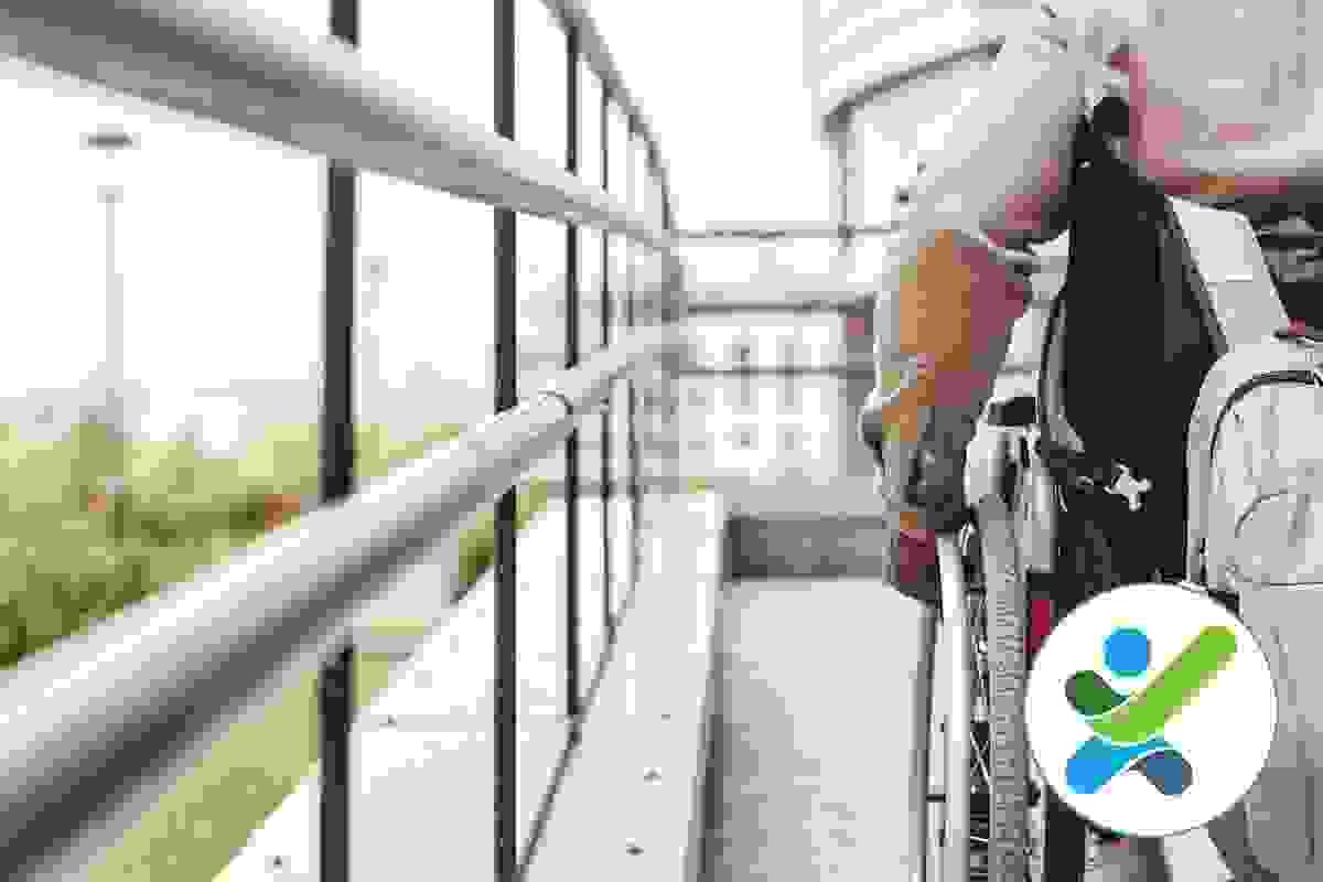 A wheelchair user is moving up a ramp with stainless steel handrails A wheelchair user is moving up a ramp with stainless steel handrails