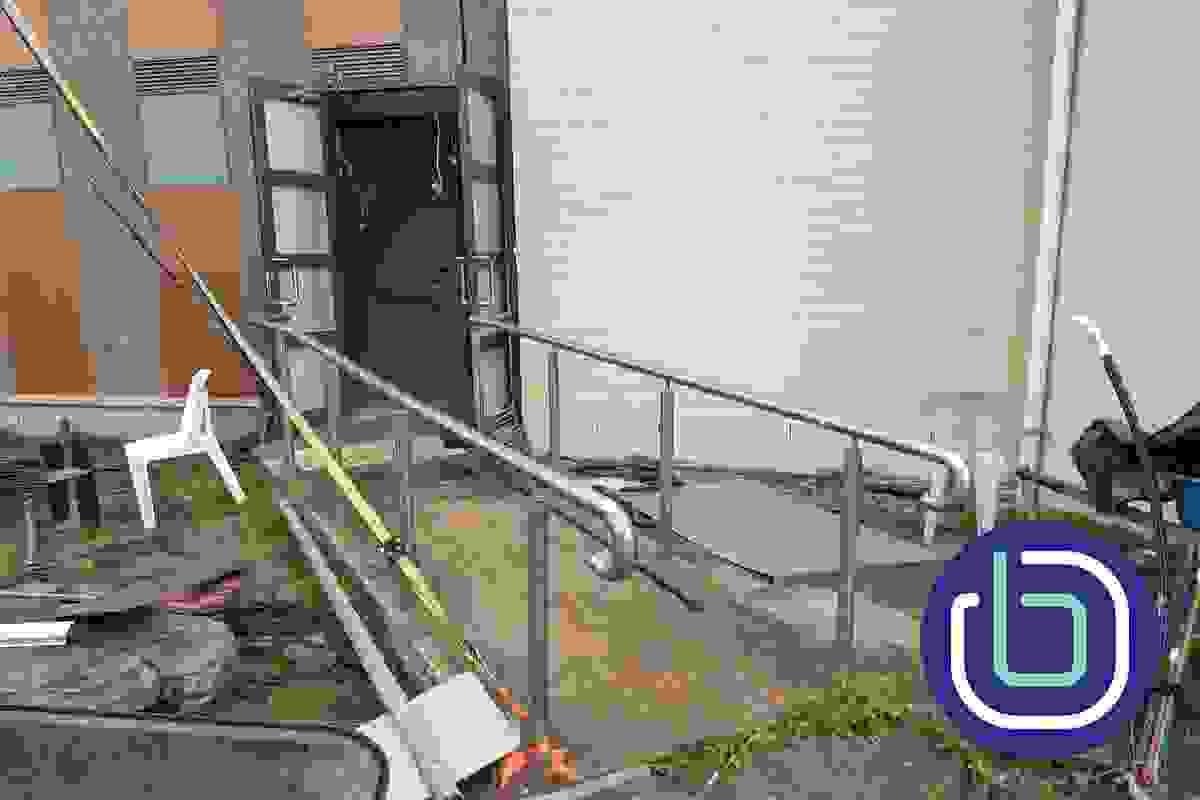 A concrete ramp and stainless steel handrails leading to a building entrance A concrete ramp and stainless steel handrails leading to a building entrance