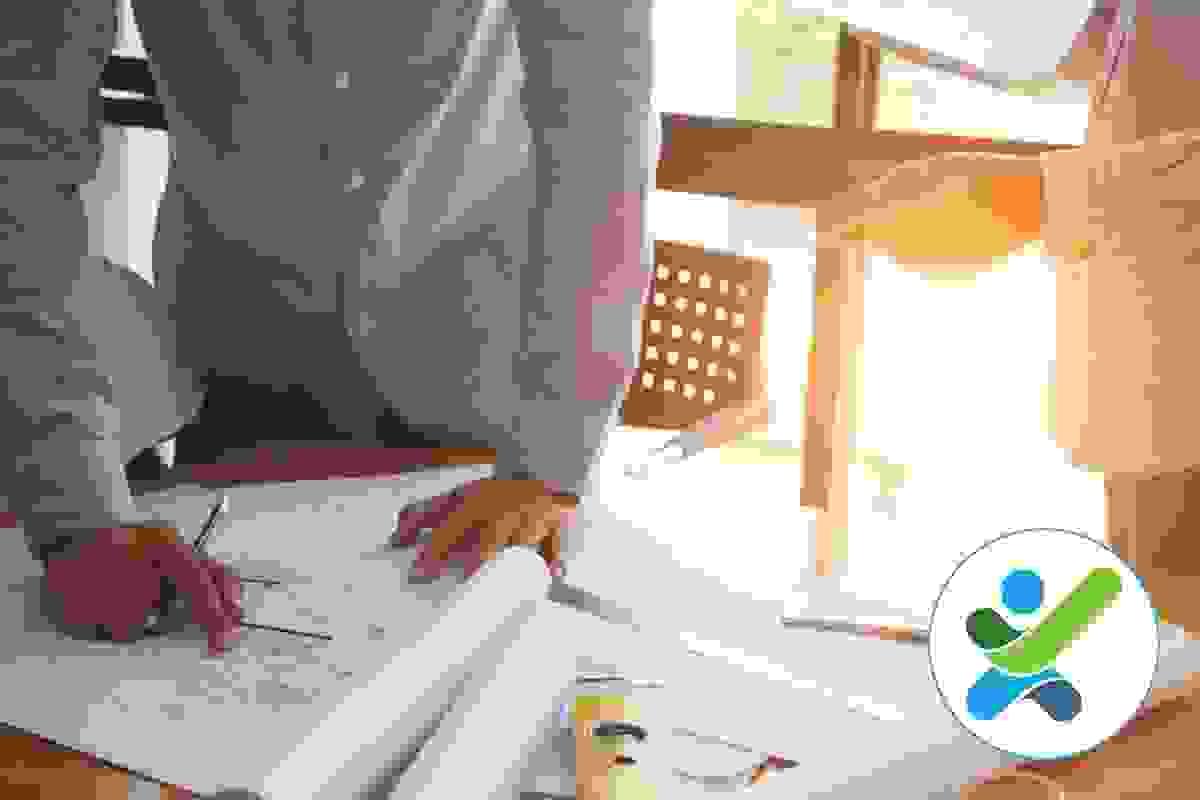 Two access consultants are standing at a desk with architectural drawings on it, one is holding a pencil and pointing at an issue Two access consultants are standing at a desk with architectural drawings on it, one is holding a pencil and pointing at an issue