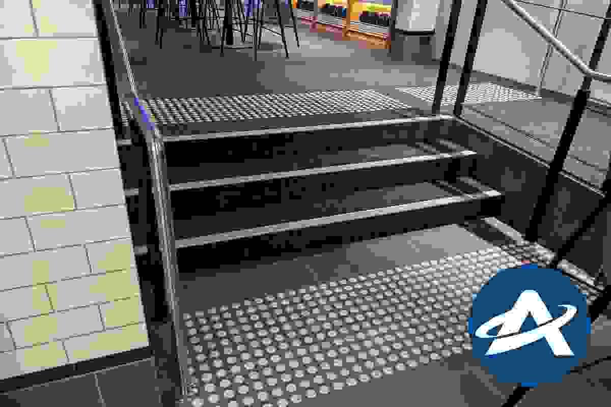 A small three step internal stairway, with black carpet, stainless steel handrails, tactile indicators, and silver coloured tread nosing strips (2) A small three step internal stairway, with black carpet, stainless steel handrails, tactile indicators, and silver coloured tread nosing strips (2)