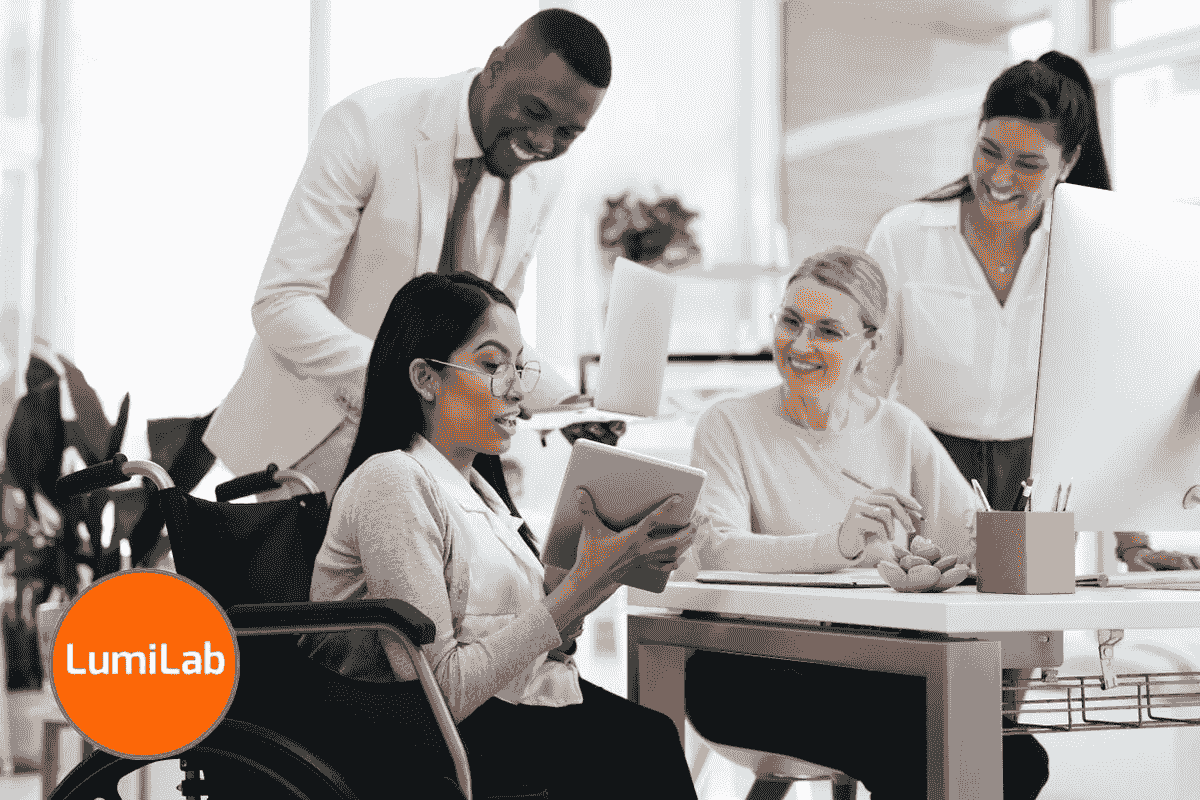 A diverse group of four colleagues, including a woman in a wheelchair holding a tablet, collaborates in an office. A diverse group of four colleagues, including a woman in a wheelchair holding a tablet, collaborates in an office.
