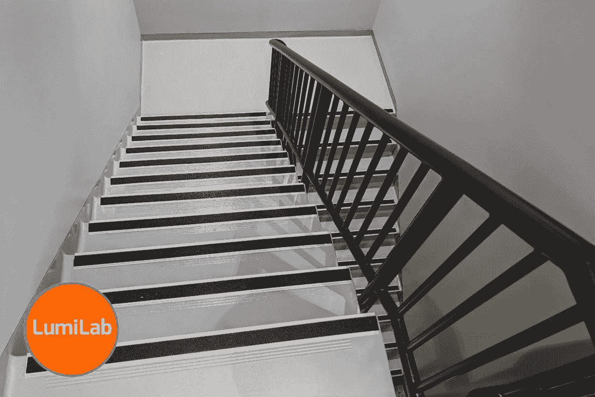A staircase with contrasting dark handrails and nosing strip on treads, viewed from above. A staircase with contrasting dark handrails and nosing strip on treads, viewed from above.