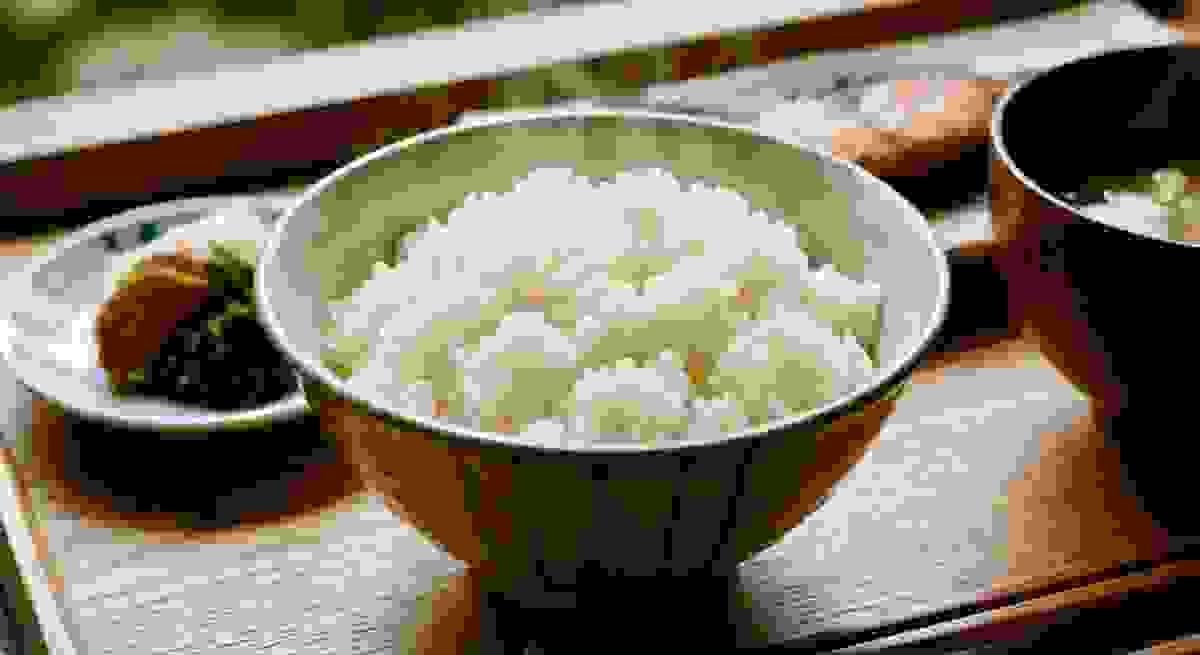 炊き立ての白ご飯と和食の器が並ぶ食卓の写真。温かさと自然な食体験を表現したイメージ。 炊き立ての白ご飯と和食の器が並ぶ食卓の写真。温かさと自然な食体験を表現したイメージ。