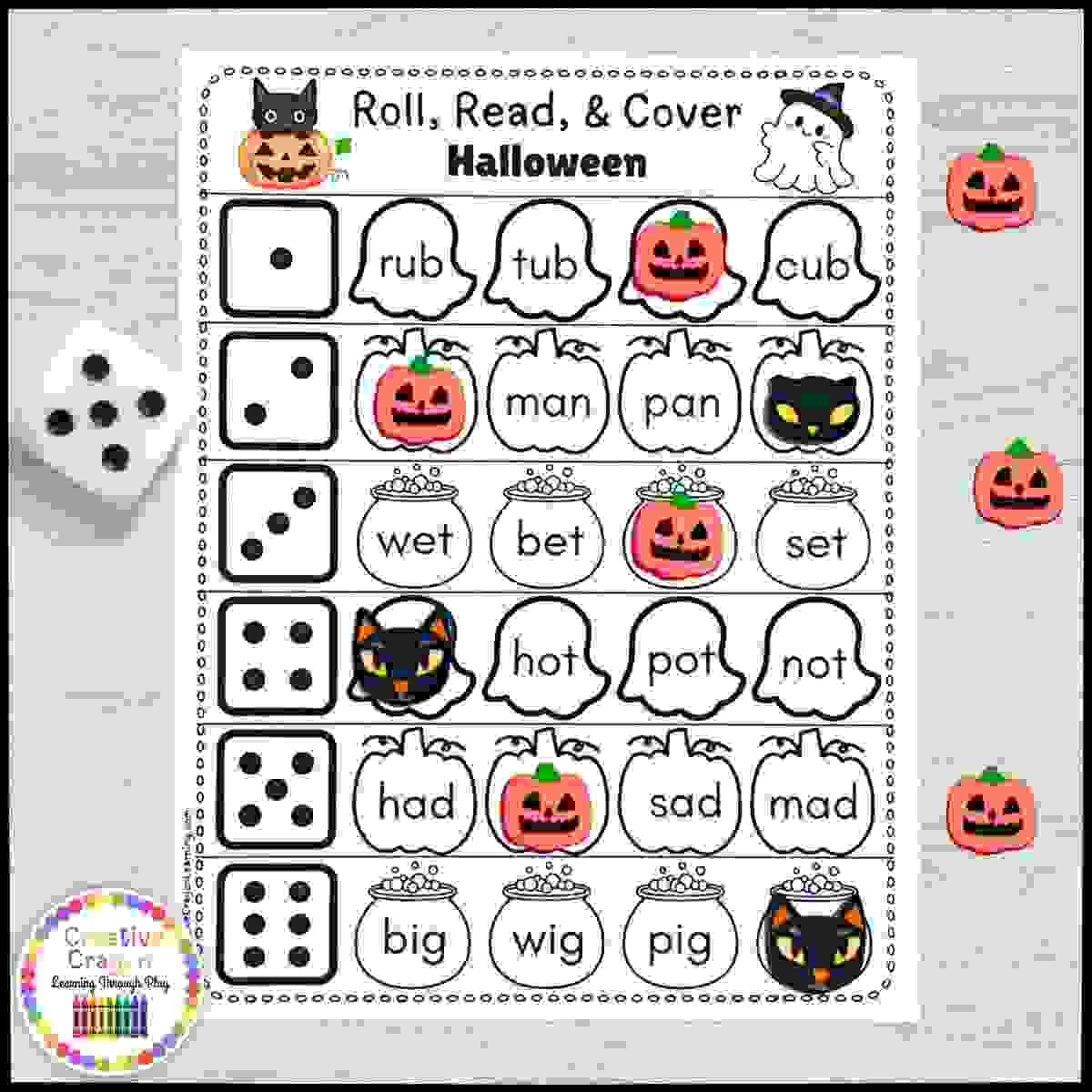 Halloween CVC word roll-and-cover literacy game for kindergarten with dice, word cards, and bingo chips.
