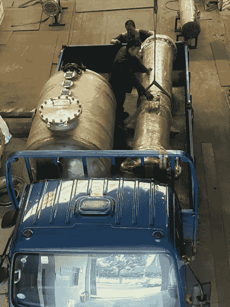Technicians securing the exchanger on a truck bed for safe transport.