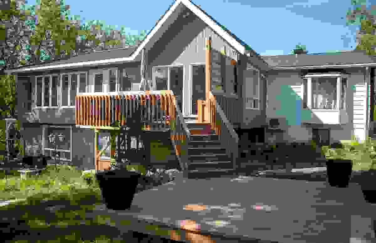Beautiful split level home, with many upgrades, a deck off the upper level with steps and railing going down to ground level open wooden patio deck.