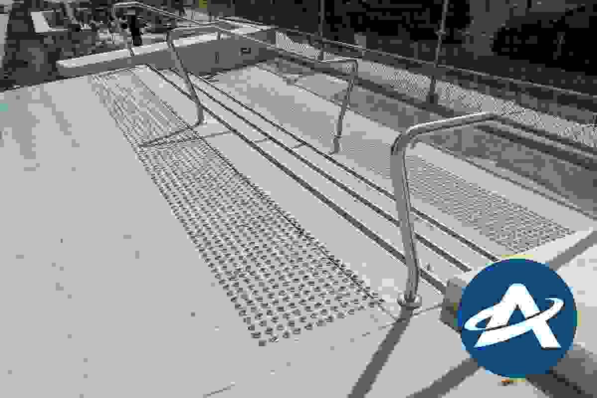 A wide three step external stairway, with stainless steel handrails, tactile indicators and tread nosing strips A wide three step external stairway, with stainless steel handrails, tactile indicators and tread nosing strips