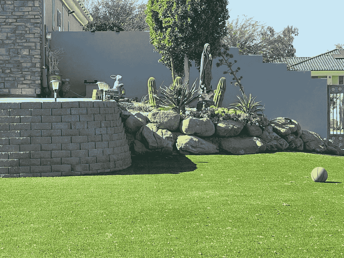Beautiful retaining wall with stone and cactus garden, artificial grass and stone work with a deocrative block wall in the background in Avondale neighborhood Beautiful retaining wall with stone and cactus garden, artificial grass and stone work with a deocrative block wall in the background in Avondale neighborhood