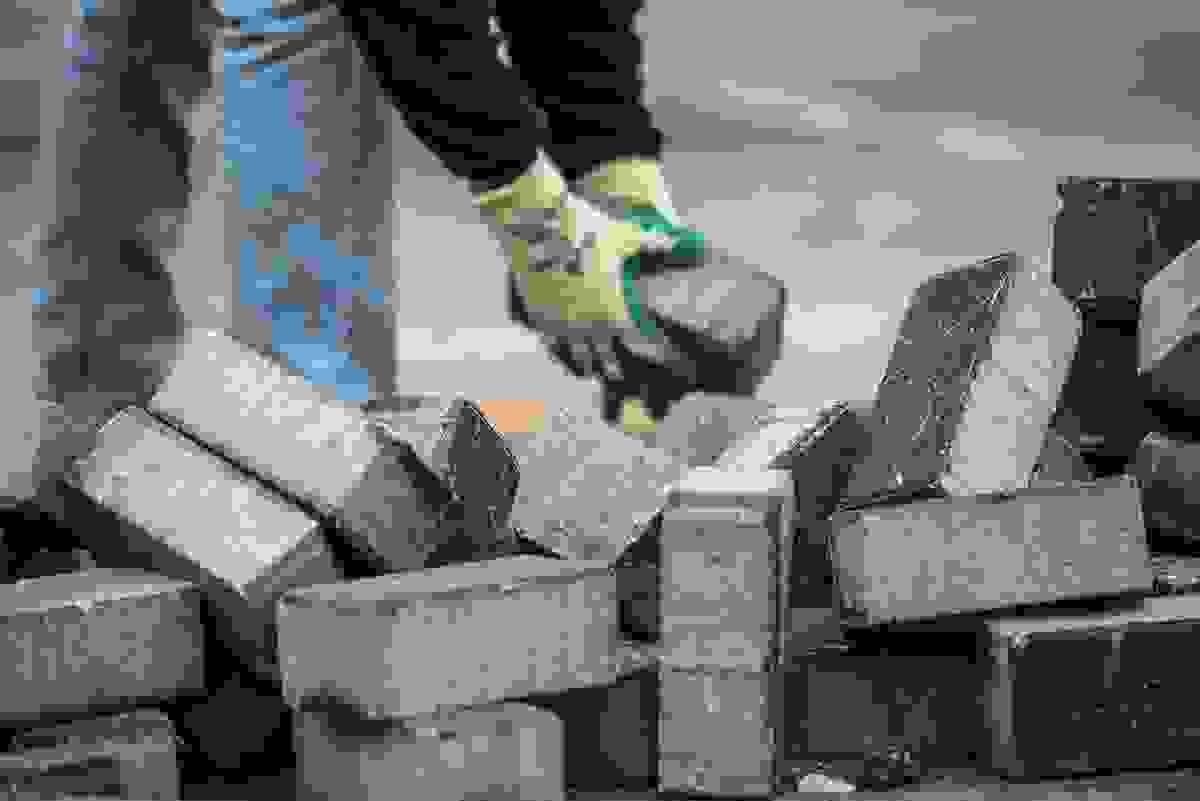 Construction worker removing blocks from area after a demolition of a concrete block wall