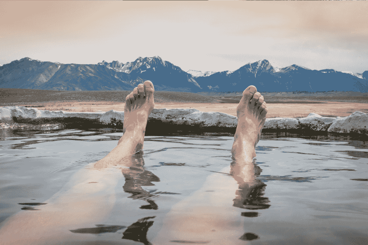 Solo traveller enjoying geothermal bath surrounded by nature