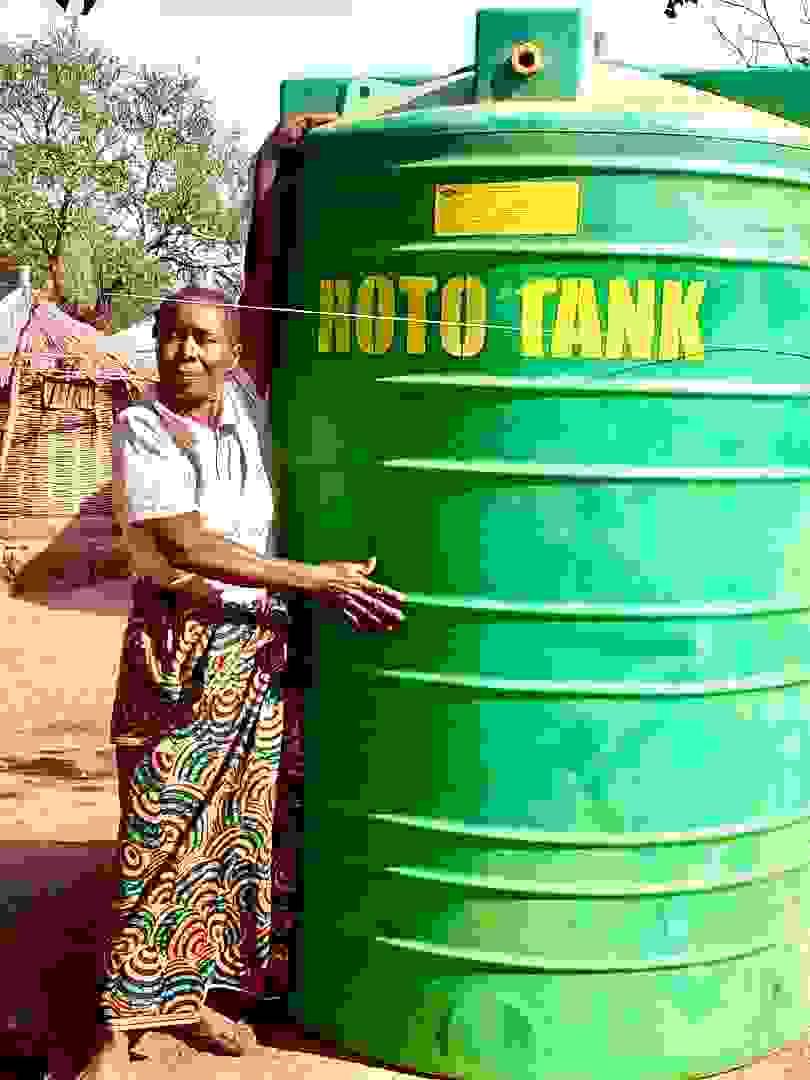 A farmer stands by a water tank.
