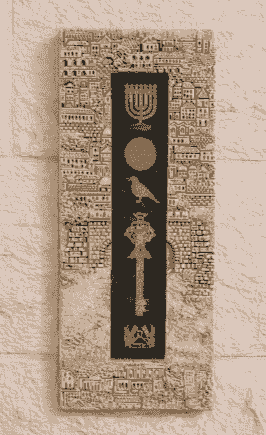 תבליט אנכי עם סמלים יהודיים, כולל מנורה ומפתח, על רקע תבליטי מבנים תבליט אנכי עם סמלים יהודיים, כולל מנורה ומפתח, על רקע תבליטי מבנים