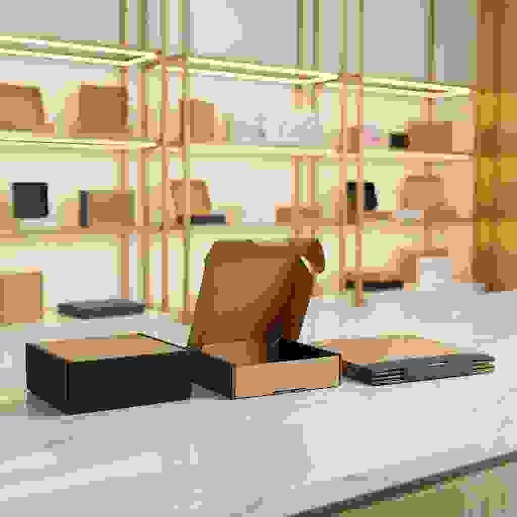 Foldable mailer box with locking tabs on marble counter, one open showing inner structure, luxury showroom blur. Foldable mailer box with locking tabs on marble counter, one open showing inner structure, luxury showroom blur.