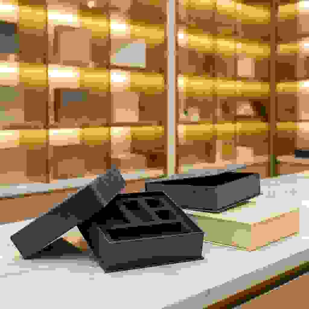 Rigid box with a precision-cut EVA foam insert, shown open on a marble counter in a luxury showroom. Rigid box with a precision-cut EVA foam insert, shown open on a marble counter in a luxury showroom.