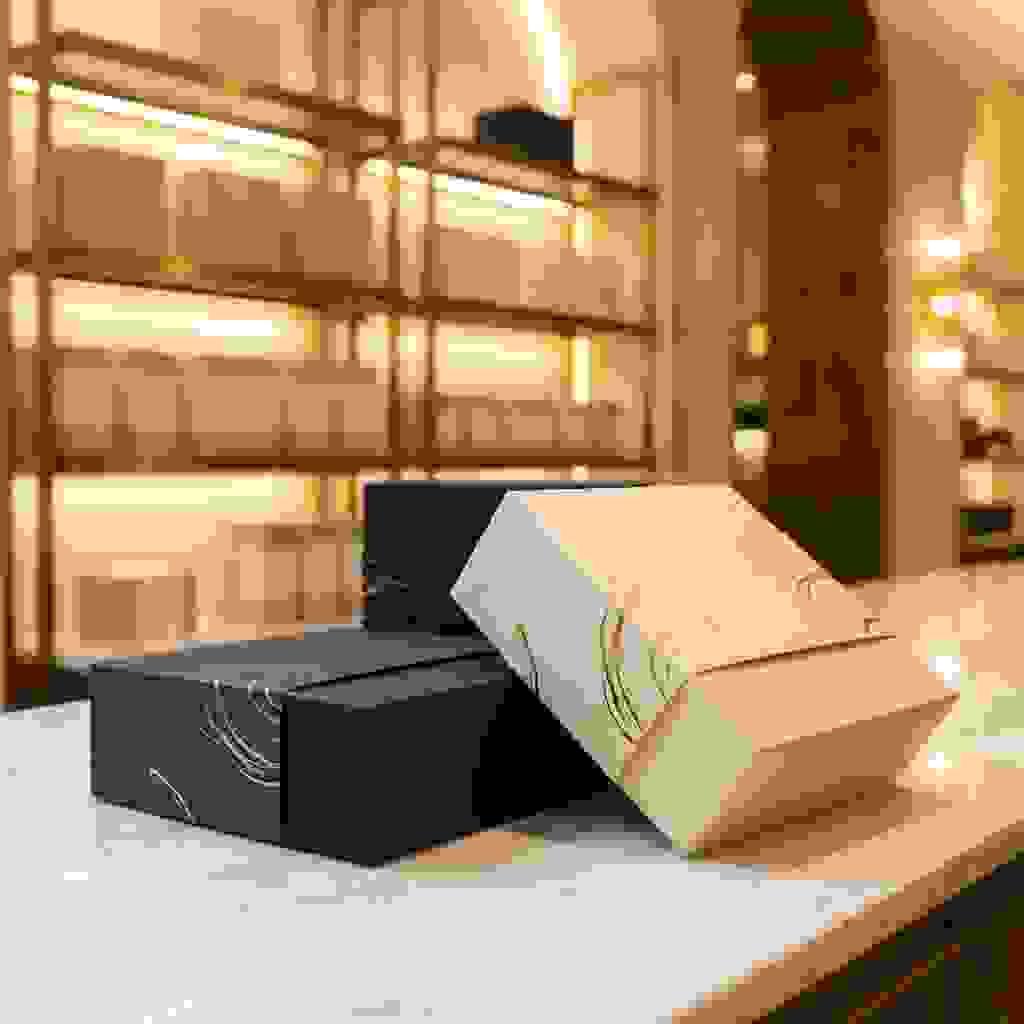 Luxury packaging sleeves with foil accents and embossed texture, wrapped around premium rigid boxes. Luxury packaging sleeves with foil accents and embossed texture, wrapped around premium rigid boxes.