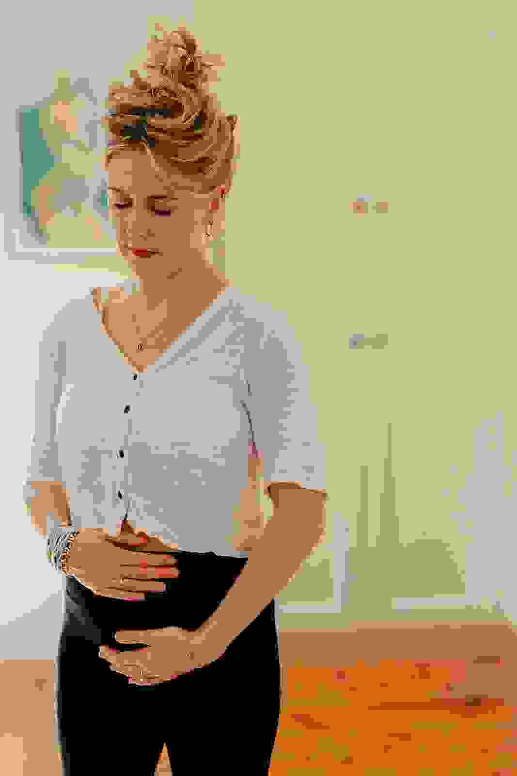 A woman in early pregnancy meditates standing holding her baby bump. A woman in early pregnancy meditates standing holding her baby bump.