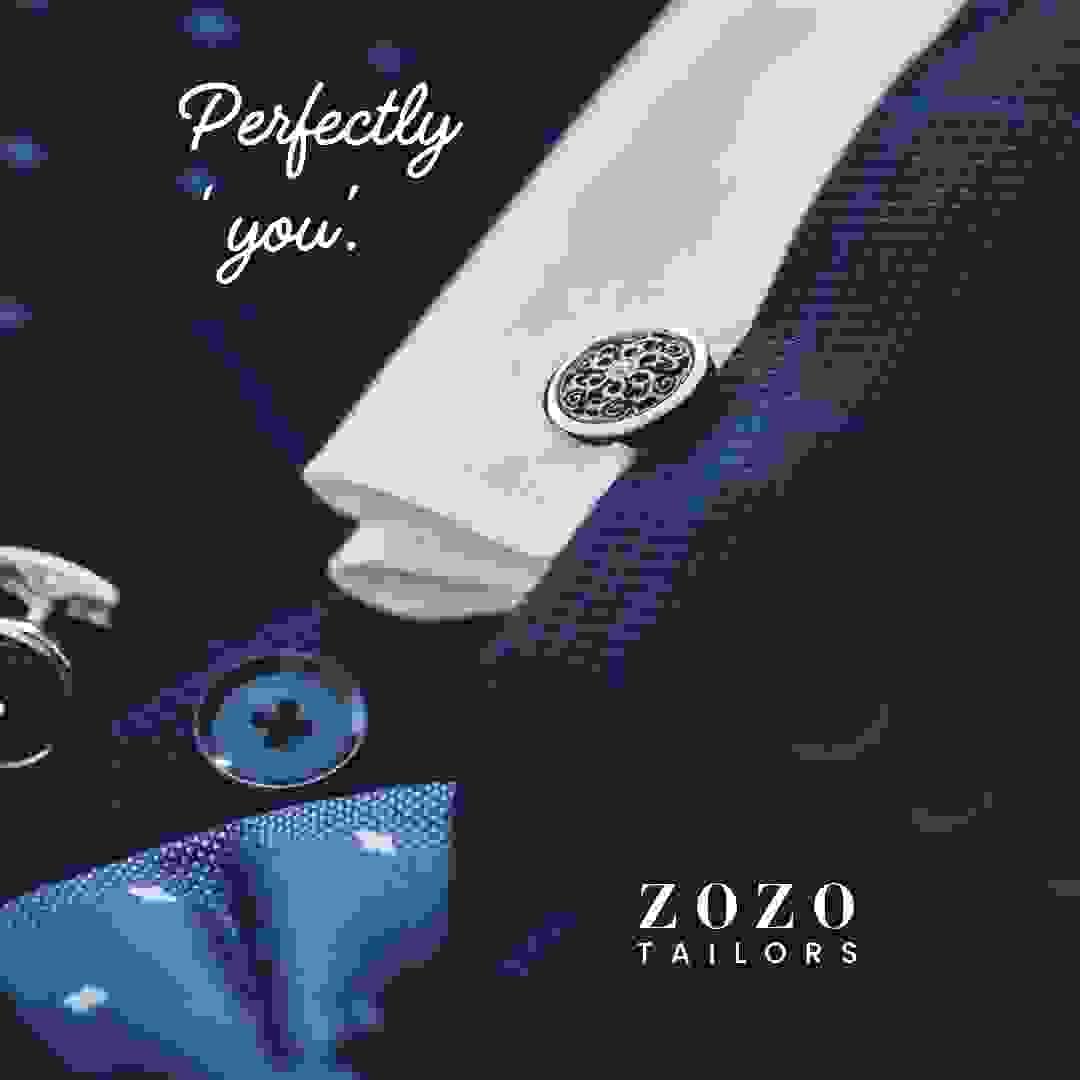 close up image of men's suit showing fabric, buttons, shirt cuff and cufflinks, with silk tie (all shown as a composition)