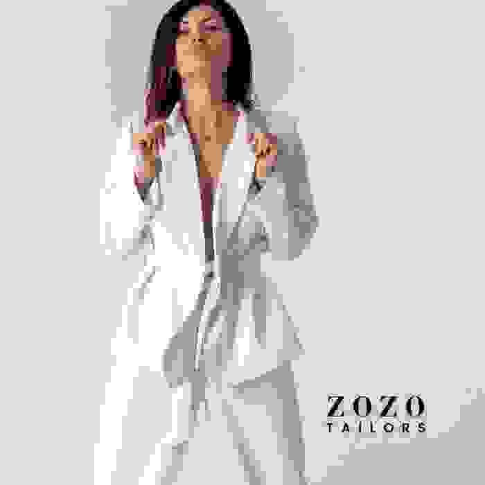Woman in bespoke white suit stands with confidence — a visual expression of individuality and precision tailoring.