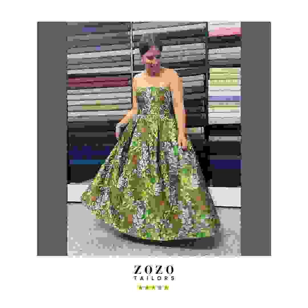 Person wearing a ball gown in satin brocade fabric, in woodland tones of green and mocha, she swirls the wid skirt. Person wearing a ball gown in satin brocade fabric, in woodland tones of green and mocha, she swirls the wid skirt.