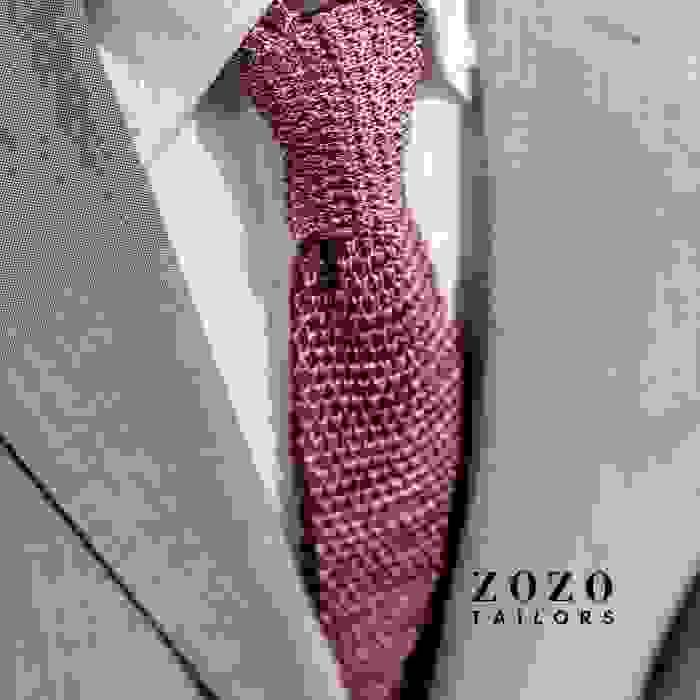 close up image of men's light coloured suit with white shirt and textured tie in a plum colour