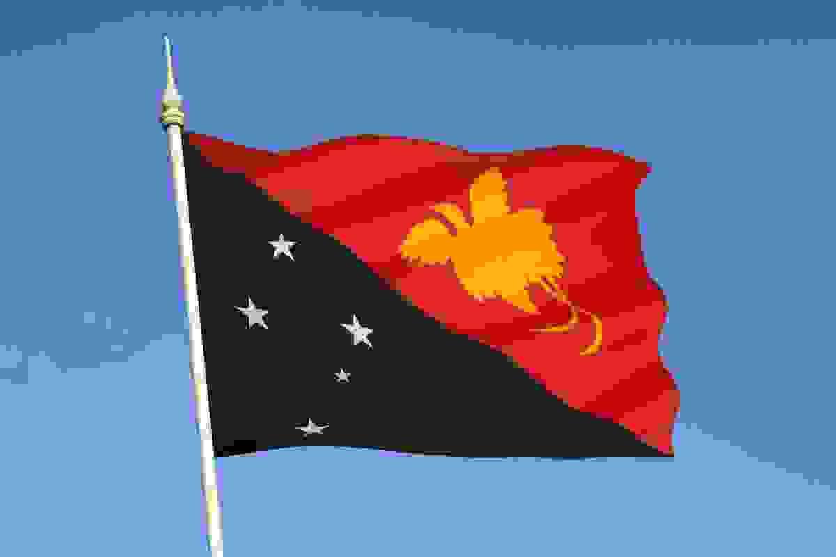 The national flag of Papua New Guinea features two diagonal sections. The bottom section features the Southern Cross constellation of stars in white on a black background. The top half of the flag features a yellow-coloured silhouette of the Bird of Paradise on a red background.