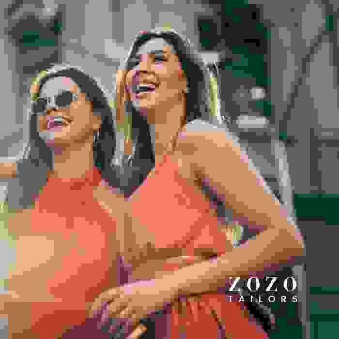 image of two happy women who are friends and on summer vacation, each wearing a tangerine dress of similar colour but in different fabric