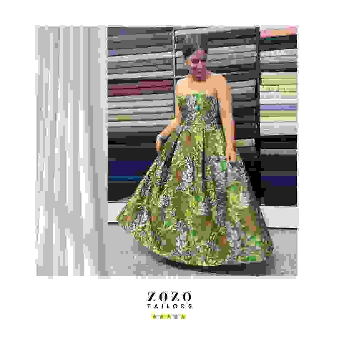 Person wearing a ball gown in satin brocade fabric, in woodland tones of green and mocha, she swirls the wid skirt. Person wearing a ball gown in satin brocade fabric, in woodland tones of green and mocha, she swirls the wid skirt.