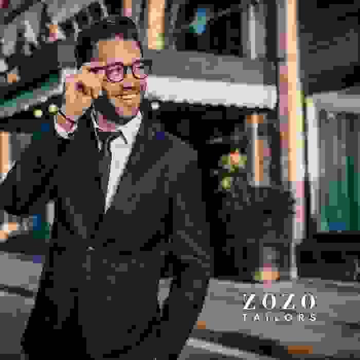 image of man in tailored suit and shirt,  strolling outside  a city building on a sunny day