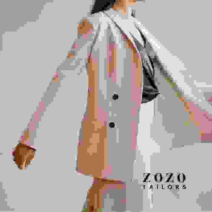 Professional woman in cream pantsuit with contrasting black silk top — elegance in motion.