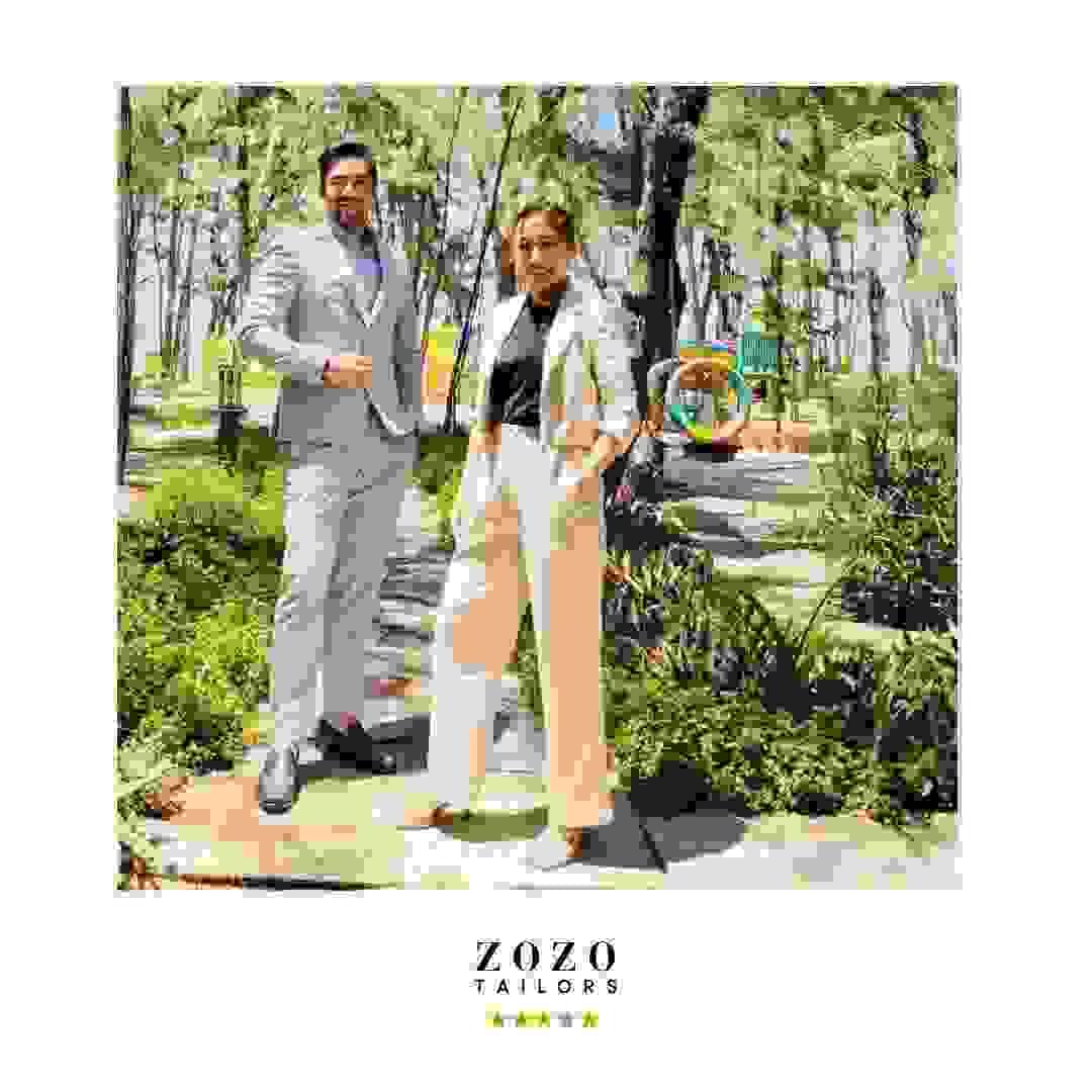 Couple wearing complementary suits: him - light-coloured tailored suit. Her: cream tailored set Couple wearing complementary suits: him - light-coloured tailored suit. Her: cream tailored set