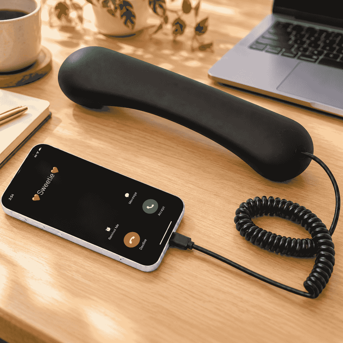Black USB-C retro phone handset connected to a smartphone for voice calls on a warm home office desk Black USB-C retro phone handset connected to a smartphone for voice calls on a warm home office desk