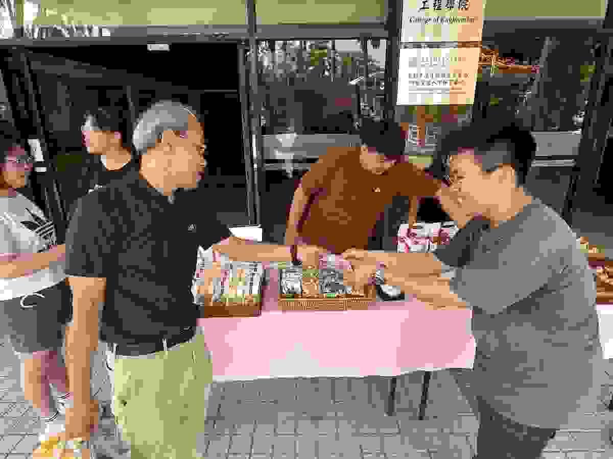 畢製團隊「暖暖堡」成員陳柏翰(右)向師長遞送商家名片