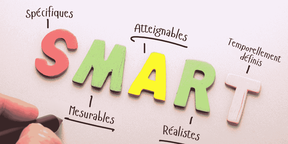 Un professionnel pointe vers un tableau blanc avec des objectifs SMART, illustrant la stratégie de communication.
