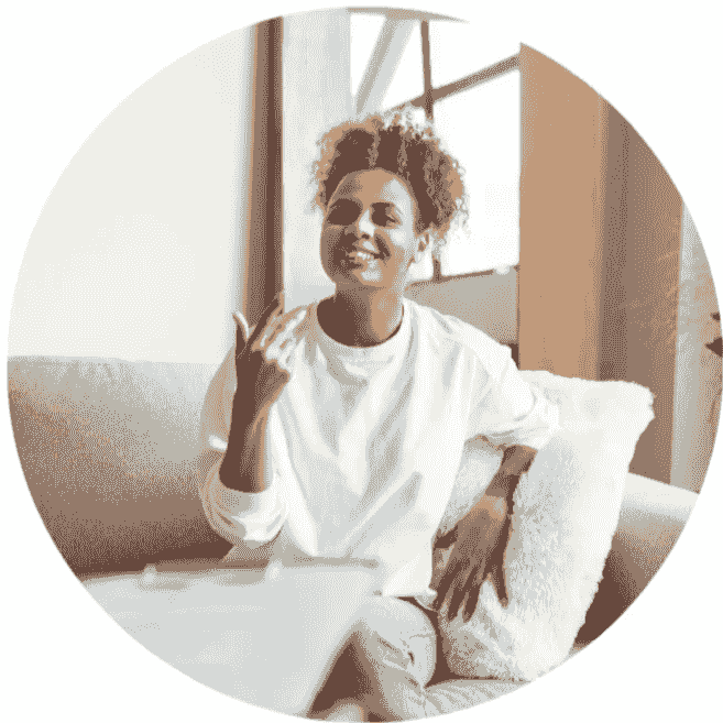 An image of a person of colour in a white shirt and jeans smiles and chats to a person hidden from the camera who holds a clipboard