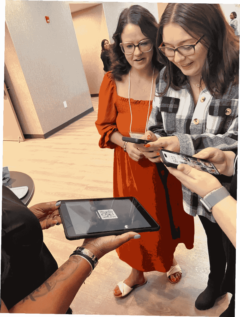 Event guests scanning a QR code held by an attendant to receive their digital photos. Event guests scanning a QR code held by an attendant to receive their digital photos.