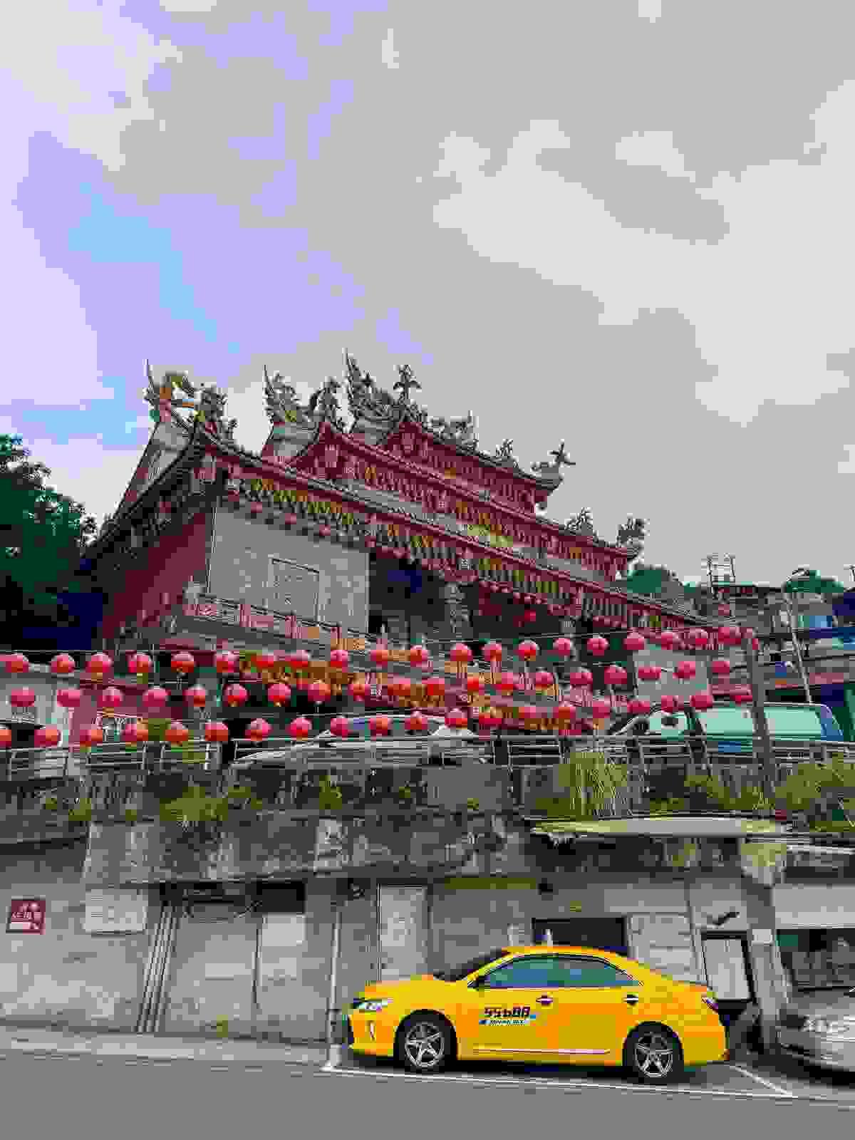 The temple at the top of the Jiufen Old Street mountain with red lanterns and yellow cab