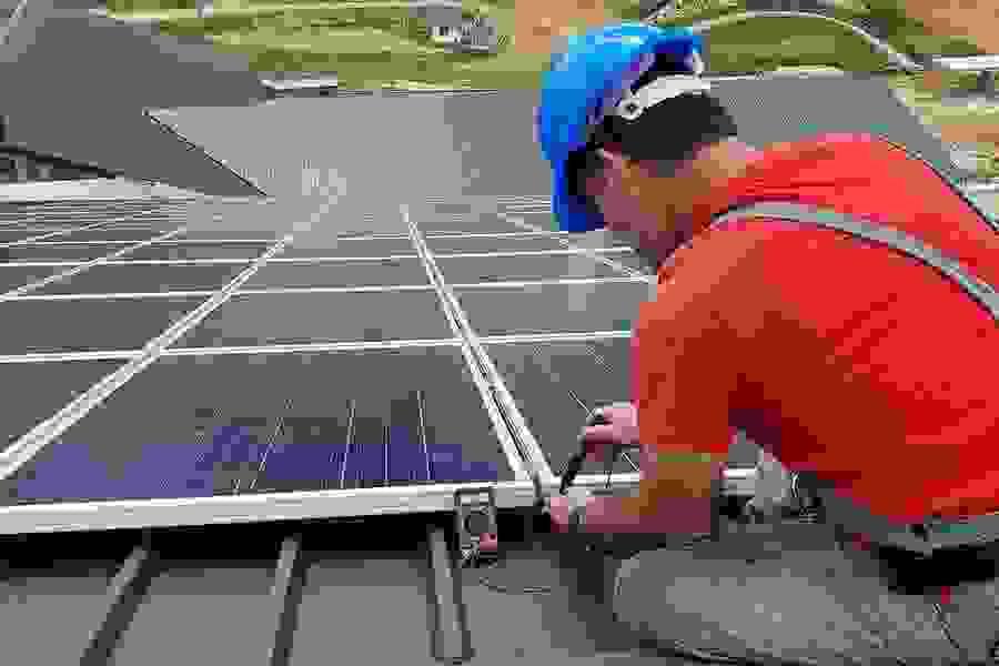 Tecnico al lavoro su un impianto fotovoltaico aziendale per verifica e manutenzione.