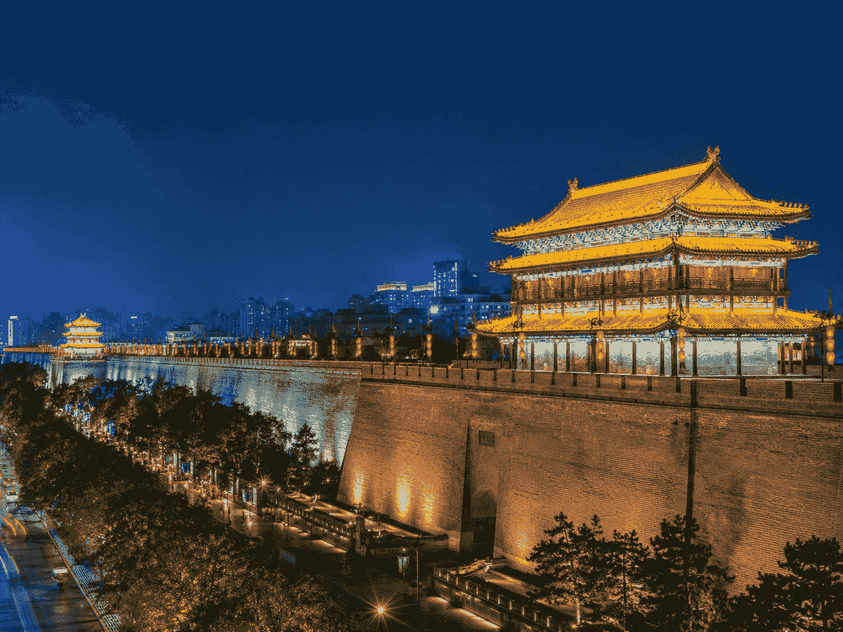 Xi’an City Wall and traditional gate tower illuminated against a deep blue evening sky. Xi’an City Wall and traditional gate tower illuminated against a deep blue evening sky.