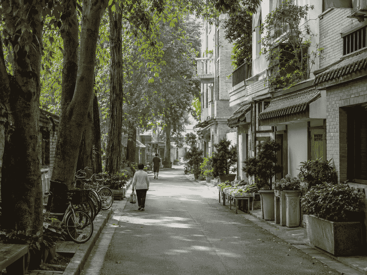 Quiet tree-lined Chengdu neighborhood with bicycles, local homes, and a produce stall. Quiet tree-lined Chengdu neighborhood with bicycles, local homes, and a produce stall.
