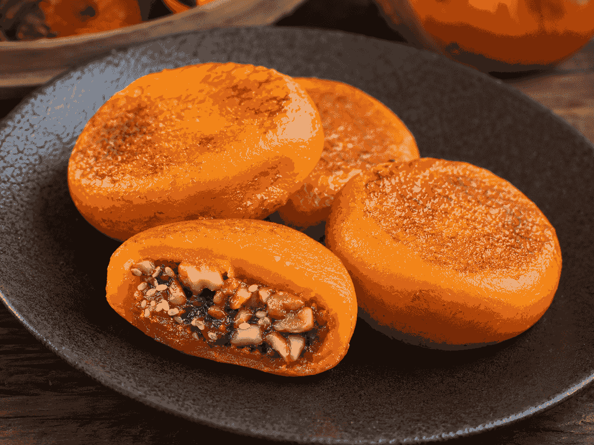 Golden Xi’an persimmon cakes with a sweet walnut and sesame filling on a ceramic plate. Golden Xi’an persimmon cakes with a sweet walnut and sesame filling on a ceramic plate.