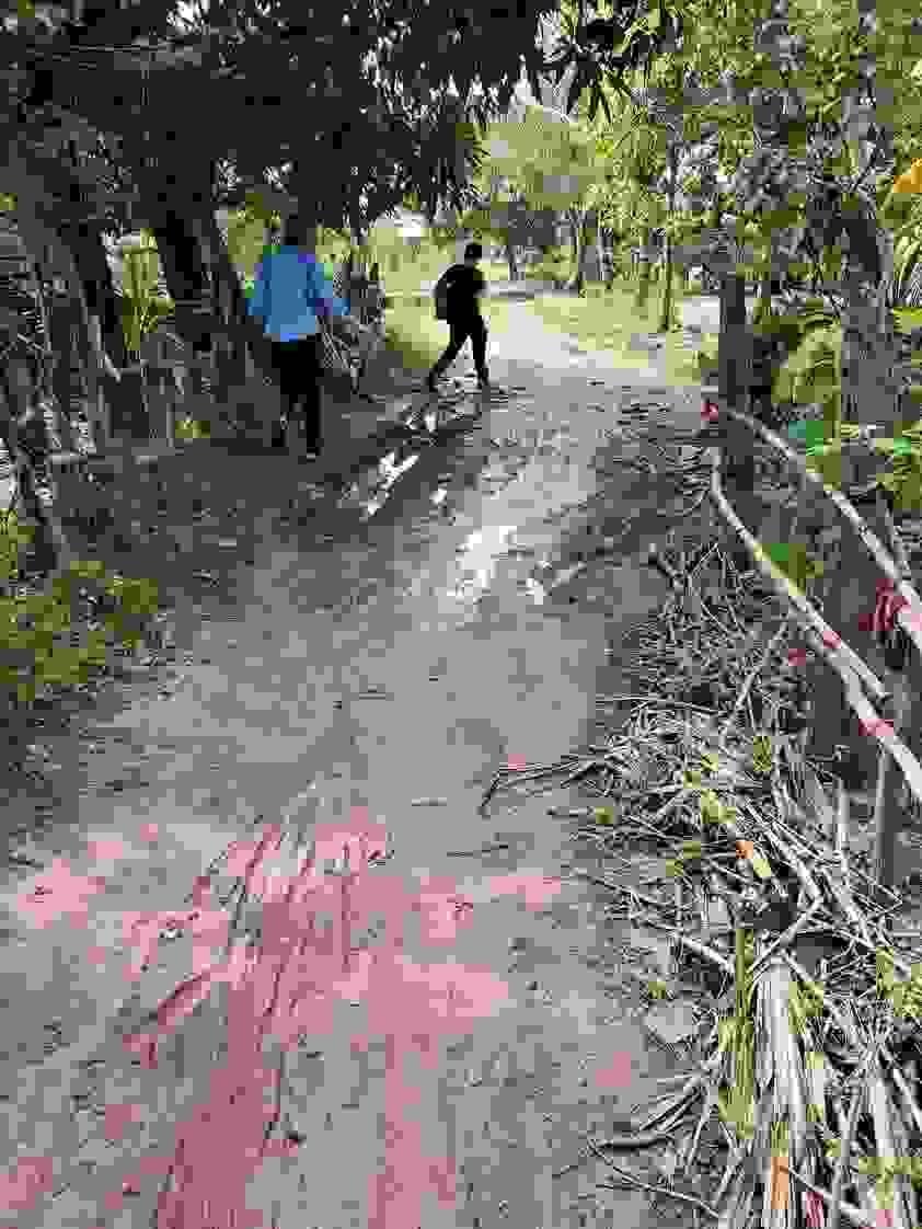 Trina & Bol navigating one of many muddy paths during some long hikes to visit remote Cambodian "well" families