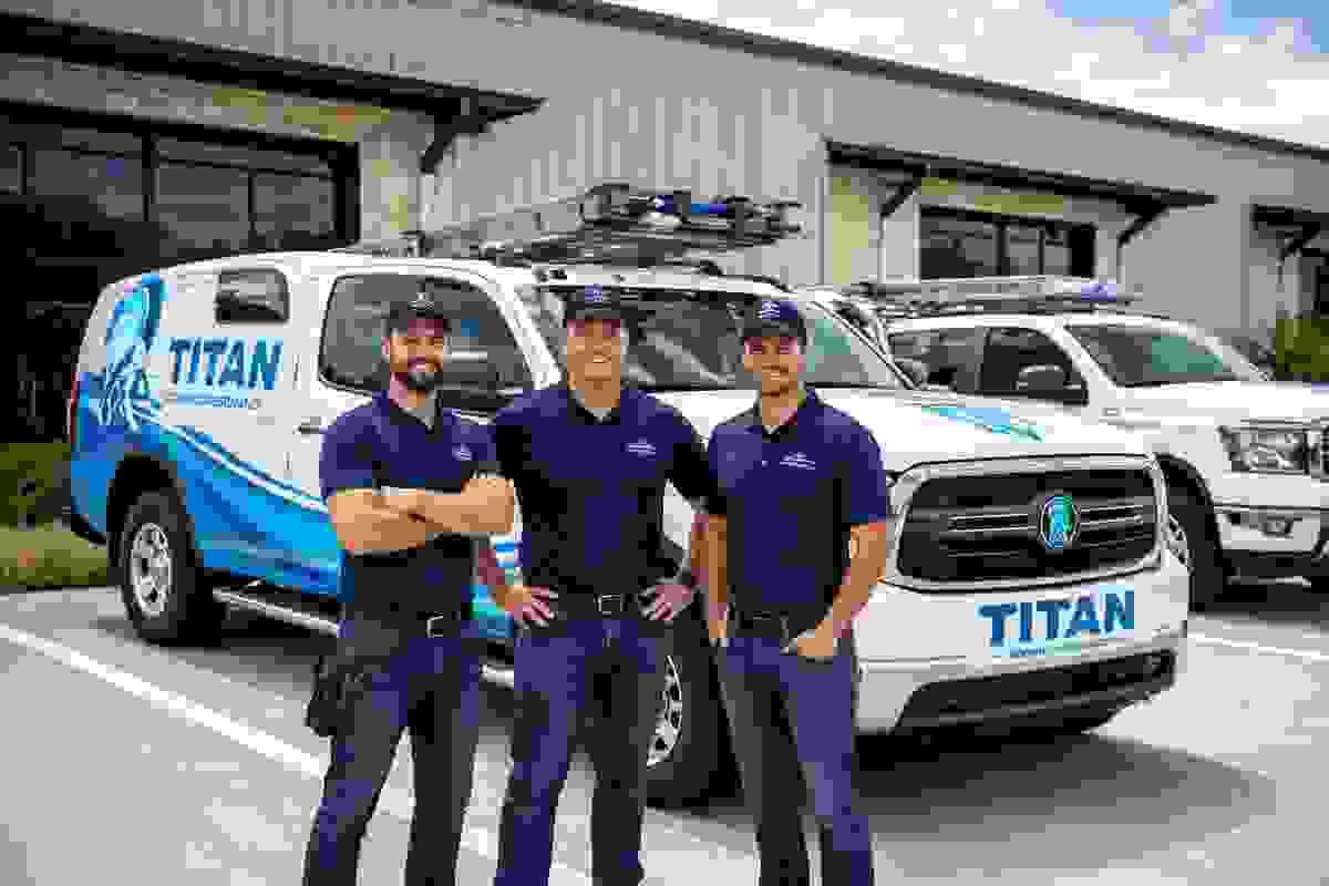 Titan Roofing & Restoration team standing in front of branded service trucks outside company building in Austin, Texas Titan Roofing & Restoration team standing in front of branded service trucks outside company building in Austin, Texas