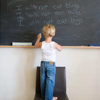 Boy writes with his left hand on a chalk board.