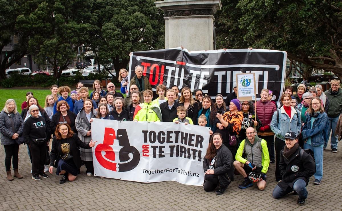Communities gather at Parliament behind 15 year old Jack Karetai-Barrett, who cycled nearly 1000kms to deliver a letter to the Prime Minister in support of Māori wards. Supporters hold up massive Toitū Te Tiriti and Together for Te Tiriti banners. 