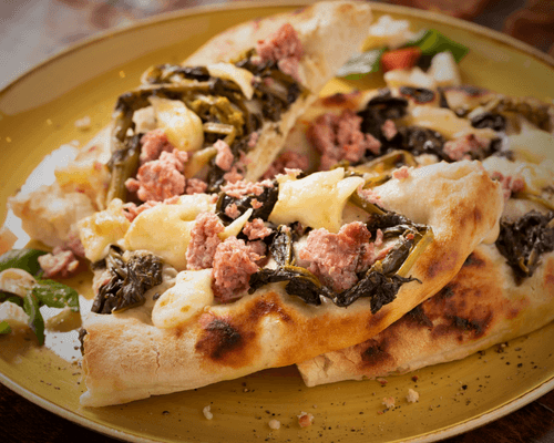 Fresh mozzarella melted on a flatbread with sausage and greens.