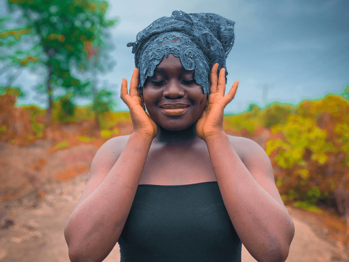 african woman with blue headscarf with heads to hand in meditative posture