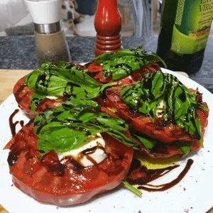 Cherokee Purple beefsteak heirloom tomato cut to show dusky rose hues, whole fruit blurred in background, grown chemical-free in Hokianga, Northland, New Zealand.
