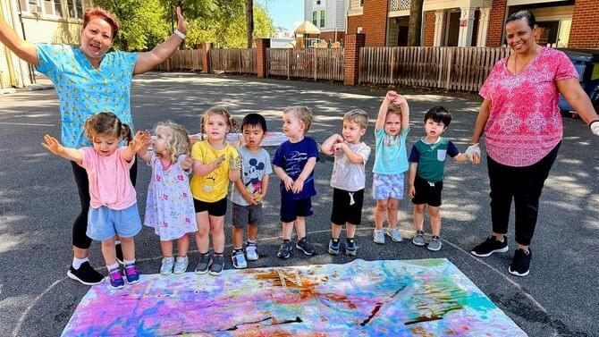 Preschoolers with teachers outdoors on colorful markers art during Spanish enrichment program at Ballston Children’s Center in Arlington County.