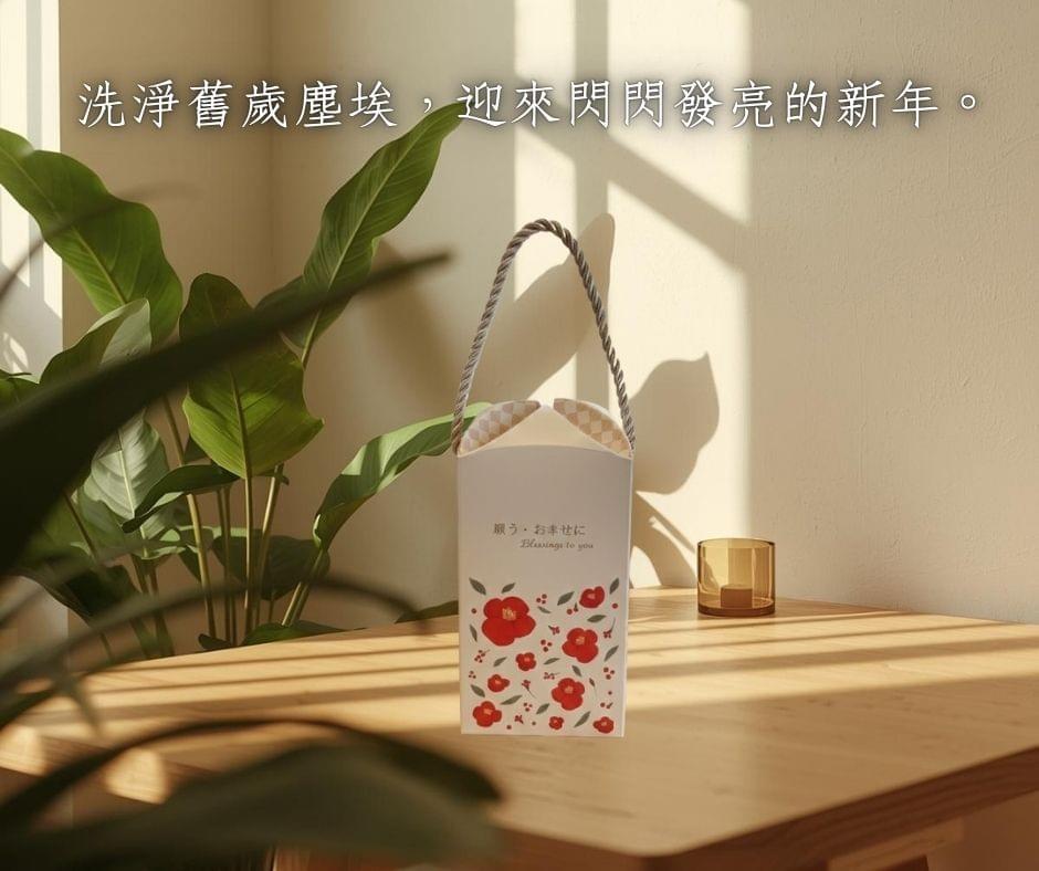 日初而皂山茶花圖樣手提禮盒，置於木質桌面上，陽光透過葉片灑落的光影